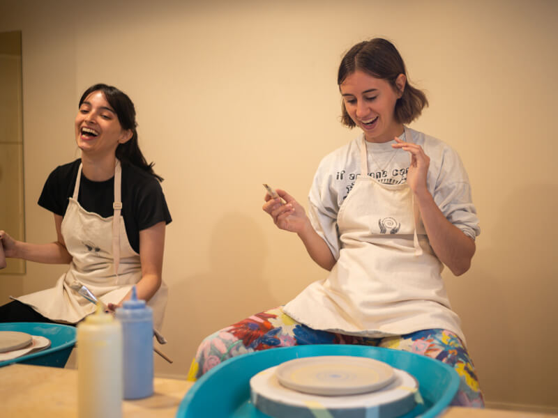women laughing at wheel throwing class